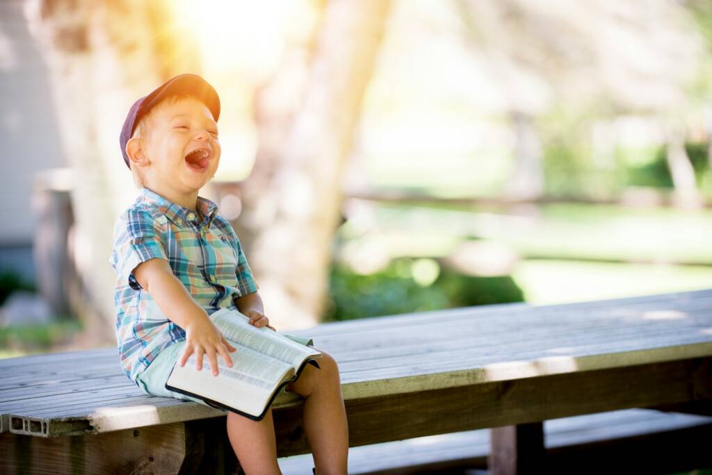 boy sitting on bench while holding a bible